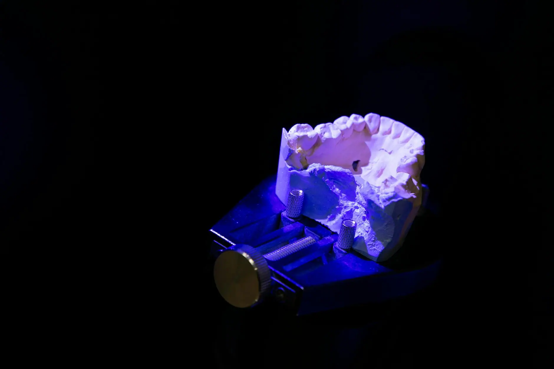 From above of white dental impression for creating denture placed on table in darkness illuminated by blue light against black background